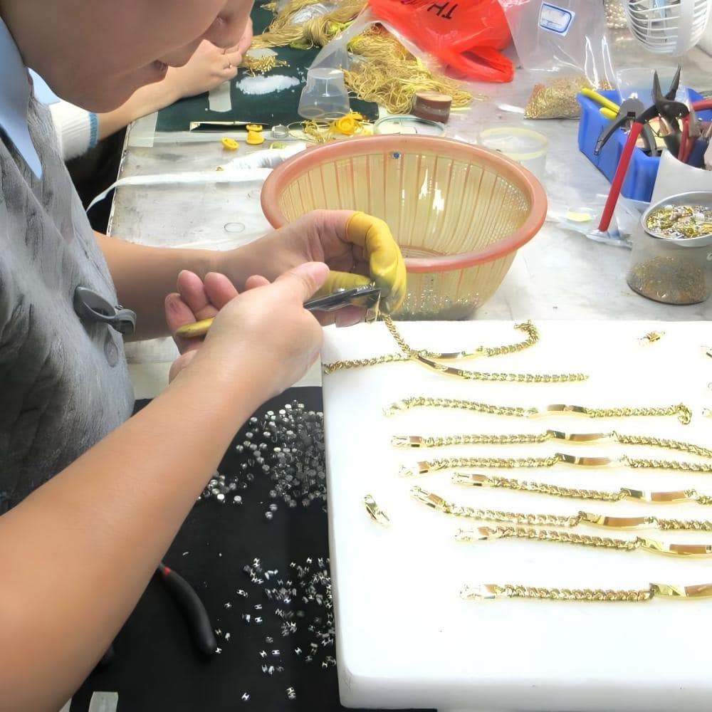 Technicians assembling stainless steel jewelry at a production workbench